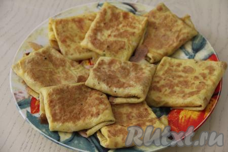 Готовый яичные блин, фаршированный ветчиной и сыром, переложить на тарелку. Смазывая сковороду маслом перед жаркой очередного блина, постепенно приготовить все конвертики с ветчиной и сыром (у меня получилось 8 штук).