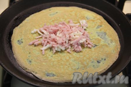 Аккуратно перевернуть яичный блин и выложить на середину 1 столовую ложку начинки из ветчины и сыра.