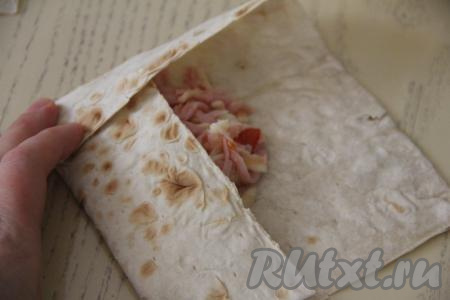 Подвернуть края лаваша на начинку, формируя конвертик.