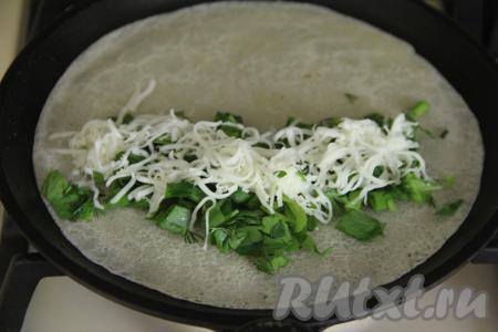 Перевернуть блин. Зрительно поделить его на две части. Выложить на одну половину блина примерно 1 столовую ложку с верхом зелени, отступив от краёв. Присыпать зелень натёртым сыром.