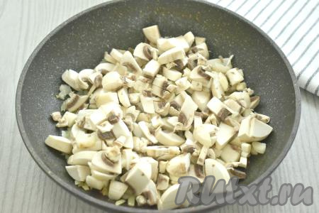 Шампиньоны промываем водой, убирая с них загрязнения, затем нарезаем на небольшие кубики и добавляем к обжаренному луку, перемешиваем. Обжариваем 2-3 минуты, время от времени, помешивая грибы с луком.