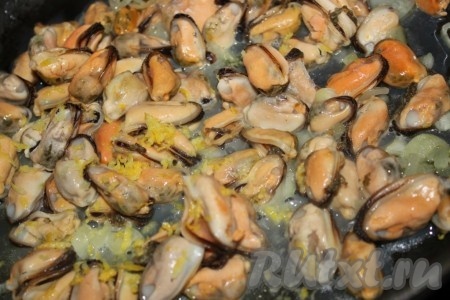 Репчатый лук нашинковать, немного обжарить на оливковом масле, добавить мидии, пожарить всё вместе около пяти минут, добавить лимонную цедру и полить лимонным соком.