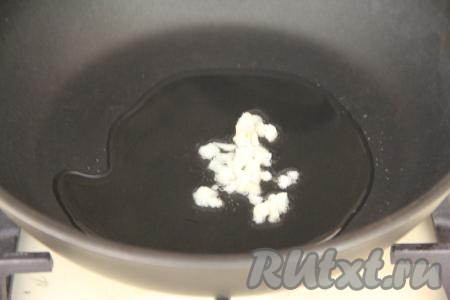 В сковороду влить растительное масло, разогреть, выложить мелко нарезанный зубчик чеснока и обжаривать его на среднем огне, периодически помешивая, в течение 1 минуты.