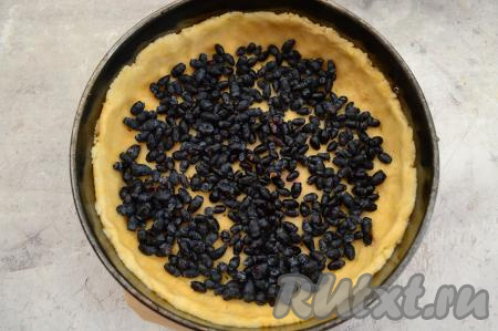 В форму для выпечки поверх песочного теста равномерно распределить ягоды жимолости.