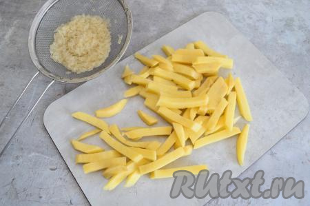 В кастрюлю наливаем 2 литра воды, ставим на огонь. Пока вода закипает, выкладываем в сито рис и тщательно промываем его под проточной водой, оставляем на пару минут, чтобы с риса стекла лишняя жидкость. Картошку очищаем и нарезаем на брусочки. В кастрюлю с закипевшей водой выкладываем картошку с рисом.