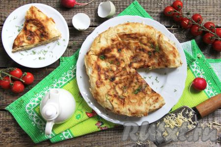 Аппетитный, сытный омлет в лаваше с сыром переложить со сковороды на тарелку, нарезать его на части и подать к столу в горячем или в остывшем виде.
