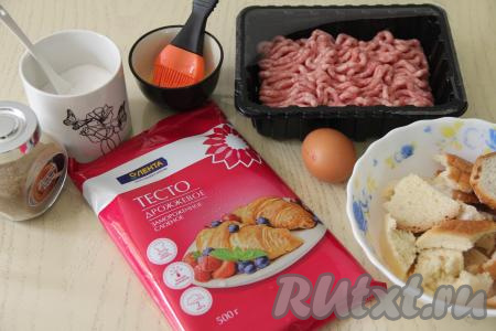Подготовить продукты для приготовления котлет в слоёном тесте в духовке. Для этого блюда можно использовать слоёное бездрожжевое или дрожжевое тесто. Достать из морозилки слоёное тесто, пусть оно размораживается при комнатной температуре. Хлеб замочить в молоке. Мясной фарш можно использовать покупной, а можно пропустить кусочки мяса через мясорубку.
