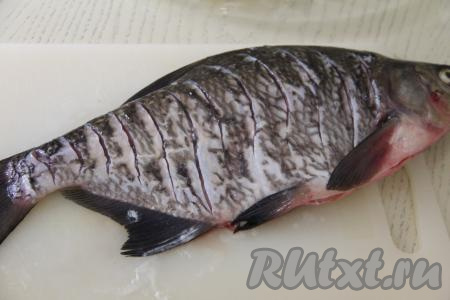 На поверхности леща с двух сторон сделать надрезы острым ножом. Натереть леща солью и специями внутри и снаружи.