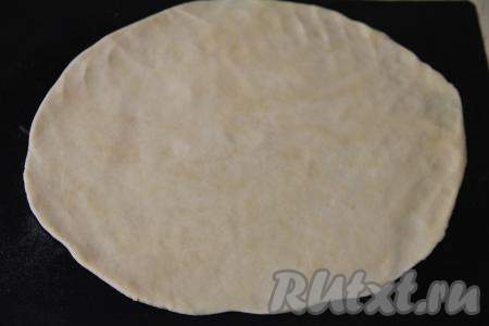 На коврике (или бумаге) для выпечки охладившееся тесто раскатать в круг диаметром примерно 30 сантиметров.
