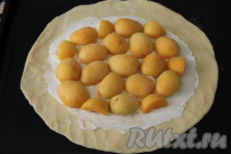 Абрикосы разрезать на 2 части, удалить косточки. Абрикосы срезом вниз выложить на тесто, смазанное творожным сыром.