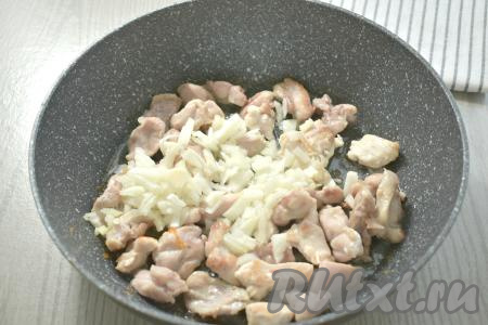 К обжаренному мясу курицы выкладываем очищенный и мелко нарезанный лук, перемешиваем. Обжариваем на среднем огне 3-4 минуты (до мягкости лука), иногда помешивая.