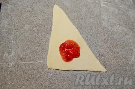 На каждую треугольную заготовку круассана,&nbsp;ближе к основанию треугольника, отступив от краёв, примерно, по 1,5 сантиметра, выложить 2 чайных ложки клубничной начинки.
