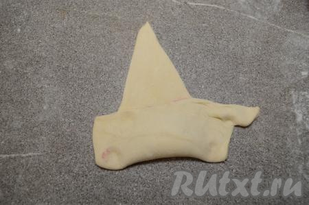 Накрыть начинку нижним краем теста и постараться хорошо прижать тесто пальцами вокруг начинки (благодаря тому, что начинка будет "запечатана" в тесто, она не будет вытекать в процессе выпечки и круассан будет хорошо держать форму).