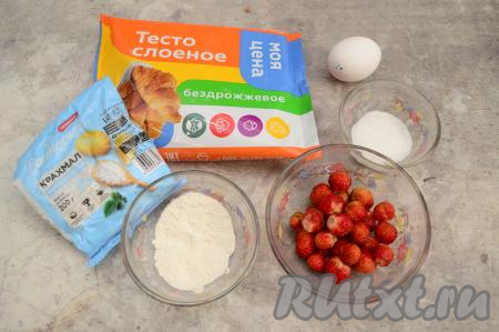 Подготовить продукты для приготовления круассанов с клубникой. Слоёное тесто заранее разморозить при комнатной температуре. Для приготовления этих круассанов подойдёт и дрожжевое, и бездрожжевое слоёное тесто. Клубнику можно взять как свежую, так и замороженную. Свежую клубнику нужно будет промыть водой, удалить чашелистики, дать немного обсохнуть. Если у вас замороженная клубника без большого количества наледи, тогда её можно не размораживать.