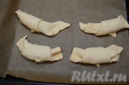 Аналогично сформировать все заготовки круассанов с клубникой и выложить их на противень, застеленный бумагой для выпечки. Выкладывать круассаны нужно на расстоянии друг от друга, так как во время выпечки они увеличатся в размерах.