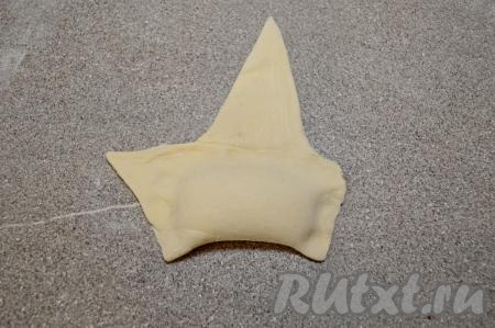 Завернуть основание треугольника на начинку, полностью закрывая творог, прижать пальцами тесто вокруг начинки (это делается для того, чтобы творог не вытекал в процессе выпечки и круассан хорошо держал форму).