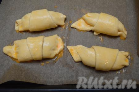 Яйцо в небольшой ёмкости слегка взбить вилкой. Смазать каждый круассан взбитым яйцом. Круассаны с творогом отправить выпекаться в разогретую до 200 градусов духовку.