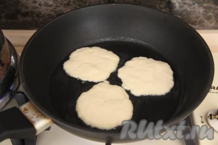 В сковороду влить растительное масло, хорошо его разогреть, после этого начать выкладывать по 1 столовой ложке теста, формируя круглые оладьи.