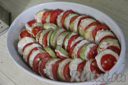 Помидоры нарезать на кружочки. В жаропрочную форму выложить под небольшим наклоном, немного внахлёст, чередуя, кружочки кабачков и помидоров.&nbsp;