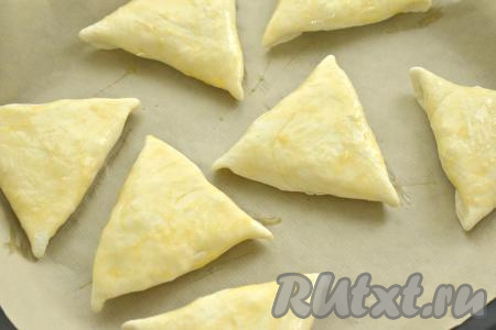 Пирожки выкладываем "швом" вниз на противень, застеленный пергаментом. Взбиваем вилкой в небольшой ёмкости сырое яйцо, а затем получившейся яичной смесью смазываем пирожки.