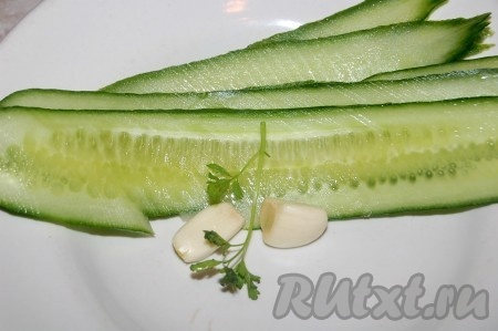 Огурцы тонко нарезать вдоль длины. Очень удобно для этого использовать ломтерезку или специальную тёрку. Приготовить зубчики чеснока.