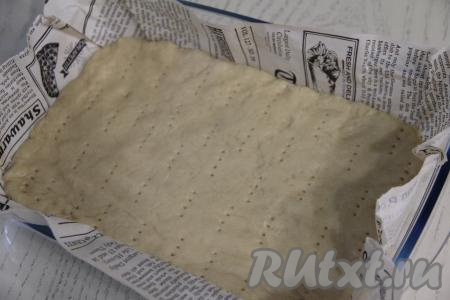 По прошествии 30 минут выложить тесто в форму для выпечки (я взяла форму размером 28 сантиметров на 19 сантиметров), застеленную&nbsp;кулинарным пергаментом. Благодаря пергаменту, готовый пирог будет проще доставать из формы и нарезать. Равномерно распределить тесто по дну формы. Бортики формировать не нужно. Наколоть тесто вилкой (благодаря накалыванию, тесто не будет вздуваться в процессе выпечки). Поставить форму с тестом в духовку, разогретую до 180 градусов, на 15 минут.