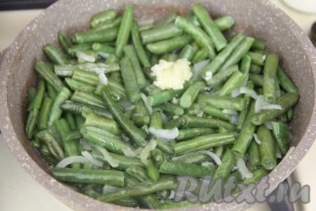 Обжарить фасоль с луком в течение 5-7 минут (если вы готовите с замороженной стручковой фасолью, то обжаривать её с луком нужно до полного размораживания и мягкости стручков), периодически перемешивая. После этого добавить очищенные и пропущенные через пресс зубчики чеснока, перемешать и обжаривать 1 минуту.