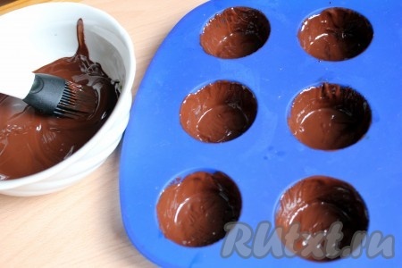 Затем силиконовой кисточкой нанести шоколад на стенки силиконовых формочек. Наносить нужно достаточно толстый слой, чтобы не было просветов, сквозь которые видны силиконовые формы. Поставить в морозилку до полного застывания (минут на 15-20).
