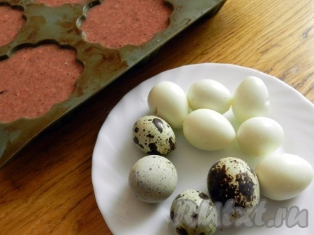 Разложить печеночный фарш по формочкам для маффинов. Перепелиные яйца отварить и очистить. Вложить в середину каждой формочки по одному перепелиному яйцу. Выпекать запеканки из куриной печени при температуре 200 градусов 25 минут.