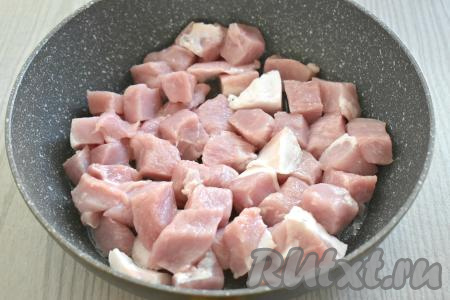 Готовить плов я предпочла в глубокой сковороде (но можно готовить и в казане или в кастрюле с толстым дном). Рис промываем проточной водой, откидываем на дуршлаг, чтобы лишняя вода стекла. Очищаем лук и морковь. Мякоть свинины моем, обсушиваем, нарезаем на кубики со стороной примерно 2 сантиметра. В сковороде разогреваем растительное масло, выкладываем нарезанное мясо и обжариваем его на достаточно сильном огне в течение 8-10 минут (до лёгкого подрумянивания со всех сторон), периодически перемешивая.