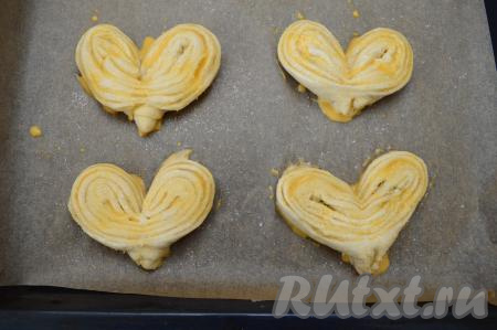 Яйцо взбить вилкой в небольшой ёмкости до однородности. Смазать каждую плюшку взбитым яйцом и присыпать примерно 1/4 чайной ложки сахара.&nbsp;