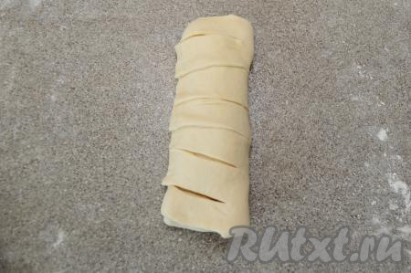 Полоски теста обернуть вокруг теста с начинкой, формируя продолговатую булочку. Сформированную слоёную булочку переложить на противень, застеленный пергаментом.&nbsp;