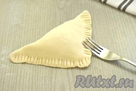 Накрываем начинку свободной стороной квадрата, формируя треугольник. Плотно скрепляем края треугольника, хорошо прижимая вилкой.&nbsp;