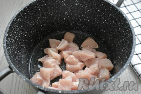 Куриное филе нарезаем на небольшие кусочки со стороной примерно 2 сантиметра. В кастрюле с толстым дном (или в глубокой сковороде) разогреваем растительное масло, выкладываем нарезанное куриное мясо и обжариваем его на огне выше среднего 7-9 минут (до лёгкого подрумянивания мяса со всех сторон), периодически перемешивая.