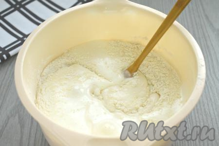 Затем в получившееся тесто вливаем смесь ряженки и соды, снова перемешиваем до однородности лопаткой. Частями всыпая оставшуюся просеянную муку и хорошо вмешивая её, замешиваем в меру густое, однородное тесто, напоминающее сметану средней жирности.