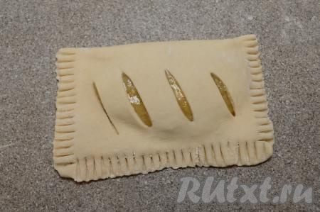 Вилкой скрепить края слойки. Если вилка в процессе скрепления краёв слойки будет прилипать к тесту, можно окунать кончики вилки в муку. Сформированную слойку сразу переложить на застеленный пергаментом противень.