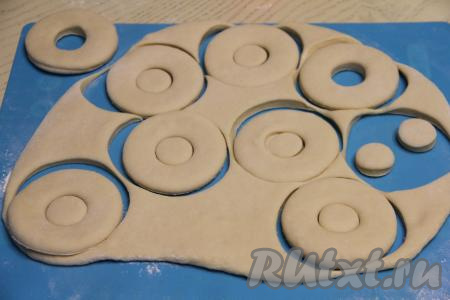 Затем, на слегка присыпанной мукой поверхности, раскатать тесто в пласт толщиной примерно 0,5 сантиметра. Вырезать пышки, я для этого использую специальную форму для вырезания пышек. Остатки теста вымесить, снова раскатать, вырезать заготовки пышек. Если у вас нет специальной формы для вырезания пышек, тогда пышки можно вырезать кружкой, а маленький внутренний круг - с помощью пробки от пластиковой бутылки.