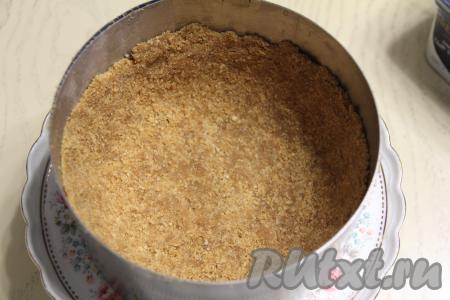 Кулинарное кольцо (или форму для выпечки без дна) диаметром 18 сантиметров поставить на подставку для подачи торта (или на плоскую тарелку). Внутрь этого кольца (или формы для выпечки) выложить массу из печенья и масла, хорошо утрамбовать, сформировав дно и бортики чизкейка. Поставить основу чизкейка вместе с подставкой для торта (или тарелкой) в холодильник на время, пока будем заниматься малиновой начинкой.