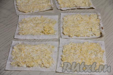 Выложить на каждый квадратик лаваша примерно 1,5 столовых ложки&nbsp;яично-сырной начинки и распределить равномерным слоем, отступив от краёв ориентировочно по 1 сантиметру.