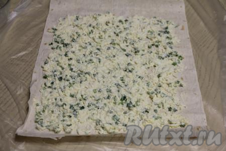 Лаваш разложить на столе. Отступив от краёв длинных сторон и одной короткой стороны по 1 сантиметру, а от края другой короткой стороны сантиметров 5, равномерно смазать лаваш яичной массой.