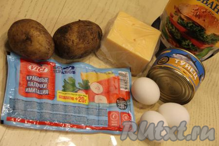 Подготовить продукты для приготовления слоёного салата с тунцом и крабовыми палочками. Яйца заранее отварить в течение 10 минут с момента закипания воды, а затем остудить. Картошку сварить в кожуре до готовности (в течение минут 25 с момента закипания воды, картофель должен легко прокалываться вилкой), затем остудить. Если крабовые палочки заморожены, их нужно полностью разморозить.