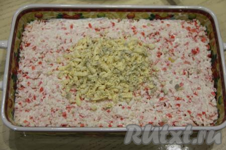 Сверху нанести решётку из майонеза и аккуратно утрамбовать. Натереть желтки на тёрке и выложить поверх крабового слоя.