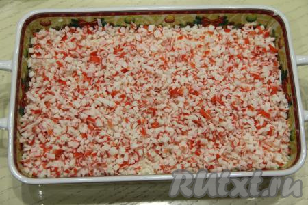 Дальше выложить слой мелко нарезанных крабовых палочек.