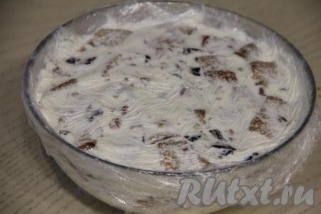 Снова выложить часть крема. Таким образом, чередуя, крем, бисквит, орехи и чернослив, сформировать весь торт. Верхним слоем должен быть крем, разровнять лопаткой. Накрыть торт сверху пищевой плёнкой, свисающей с краёв миски, слегка прижать, чтобы удалить пузырьки воздуха.&nbsp;