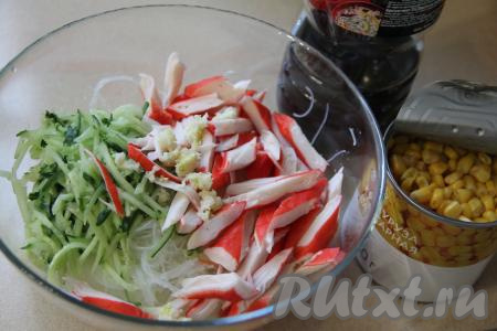 В миске соединить фунчозу, огурец и крабовые палочки, добавить чеснок, пропущенный через пресс.