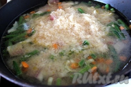 Добавьте рис и влейте горячую воду примерно на 1,5 - 2 см выше уровня рыбы с рисом и овощами.