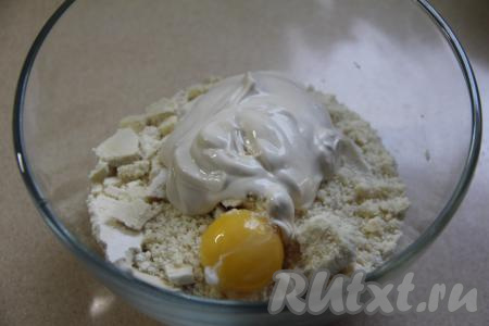 Если перемешивали муку с маслом в измельчителе, тогда переложить получившуюся масляно-мучную крошку в миску. В миску с крошкой добавить сырой яичный желток и сметану.