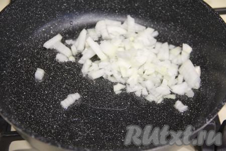 В сковороду влить растительное масло, прогреть его на достаточно сильном огне, после этого убавить огонь до среднего, выложить мелко нарезанный лук.