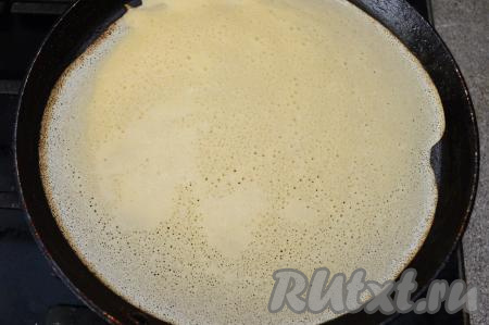 Прогреть сковороду на огне выше среднего. Перед выпечкой первого блина обязательно смазать сковородку растительным маслом. Влить небольшой половник теста на подготовленную сковороду. Слегка покачать сковороду из стороны в сторону, равномерно распределяя тесто по дну сковородки. Тесто, замешанное на топлёном молоке и кипятке,&nbsp; достаточно жидкое, поэтому оно сразу растекается по сковороде. Жарить блин до подрумянивания снизу на среднем огне.
