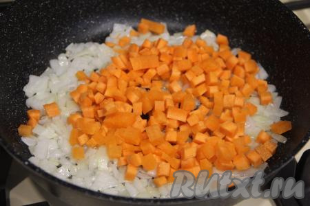 К обжаренному луку выложить морковку, нарезанную на мелкие кубики, хорошо перемешать овощи и обжаривать их 5-6 минут, время от времени перемешивая.